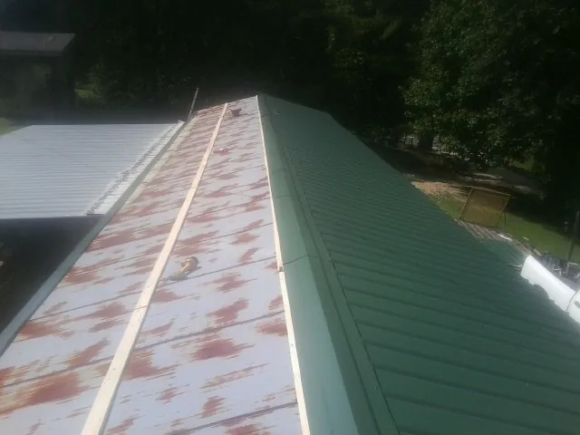 Old rusted panels beside newly installed green metal roofing — Wind Damage Roof Repair by Roofing Brothers in Palisades Park