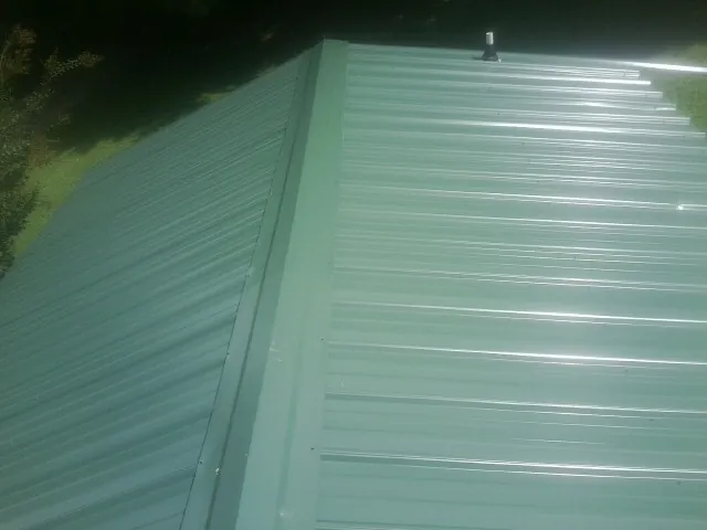 New green metal panels meeting at the ridge of a roof — Flat Roof Repair work by our crew in Palisades Park