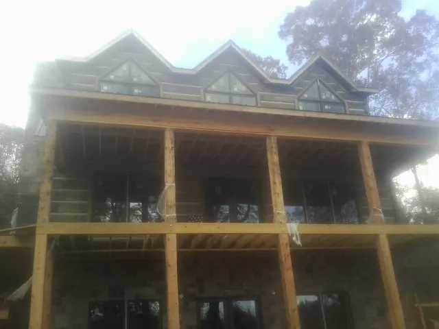 Dormers and porch framing on a large log home under construction — Roof Coating work by our crew in Palisades Park