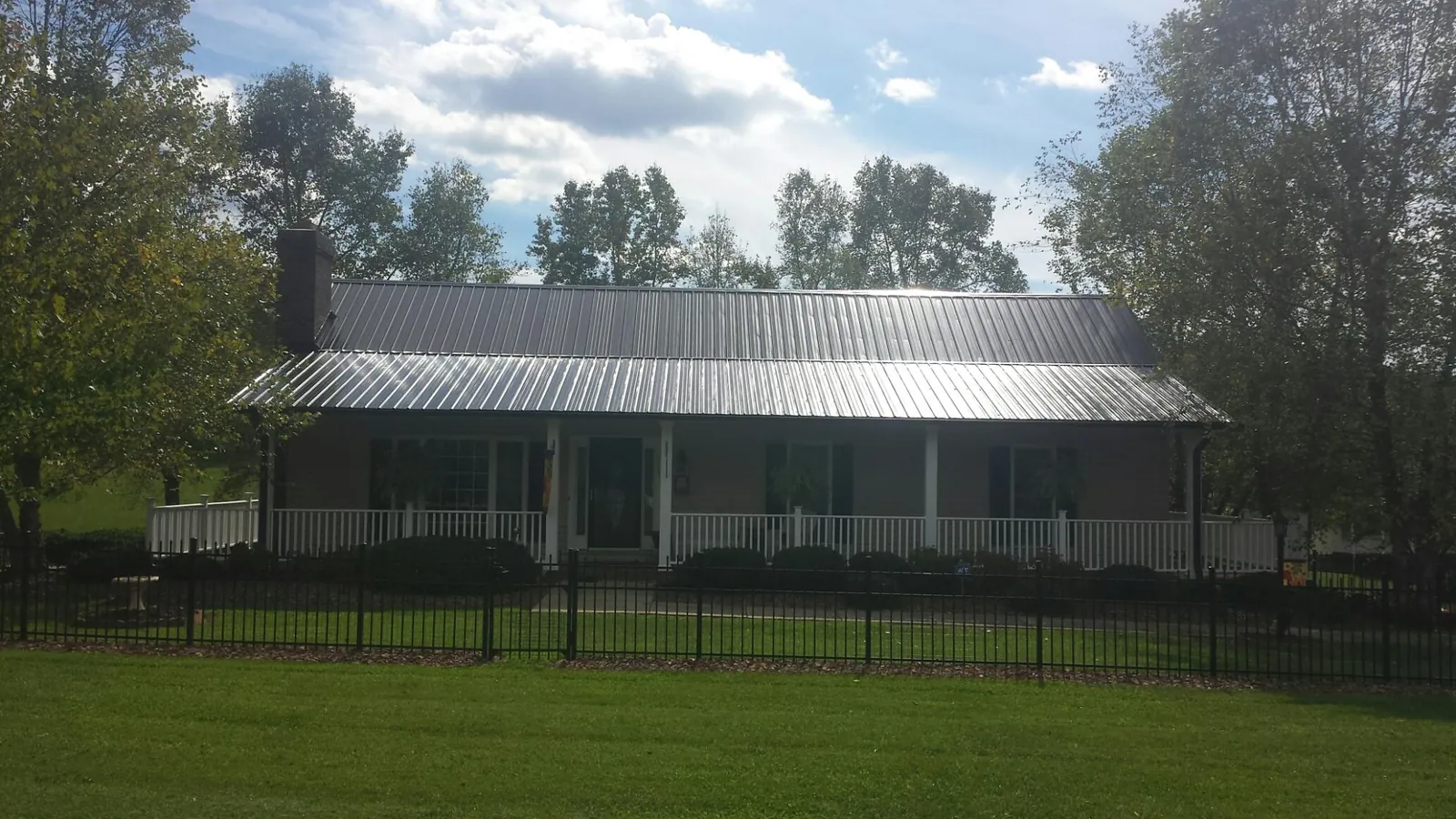 Gray metal roof on a brick ranch with a full width front porch — Gutter Guard Installation work by our crew in Palisades Park