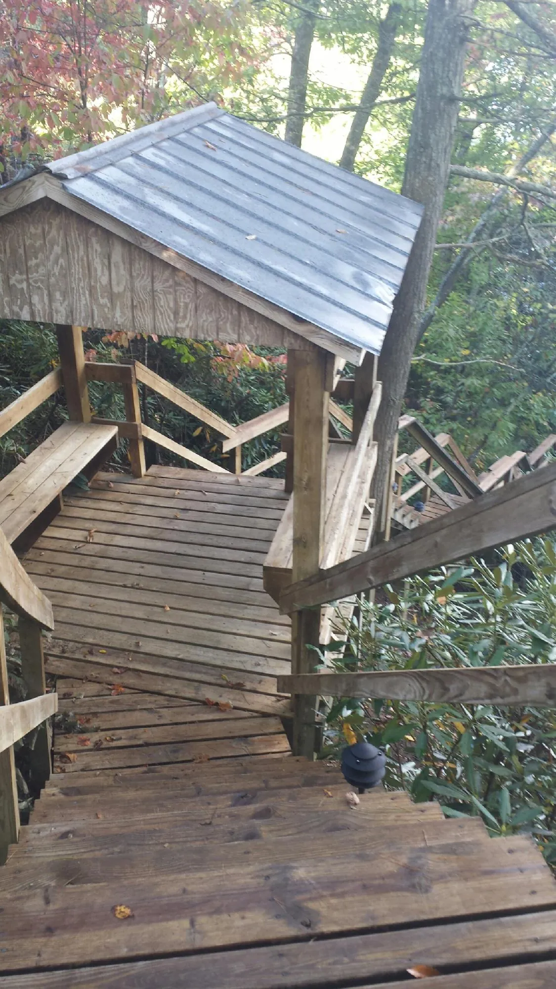 Metal roofed shelter over wooden steps on a wooded walkway — Skylight Repair & Installation work by our crew in Palisades Park