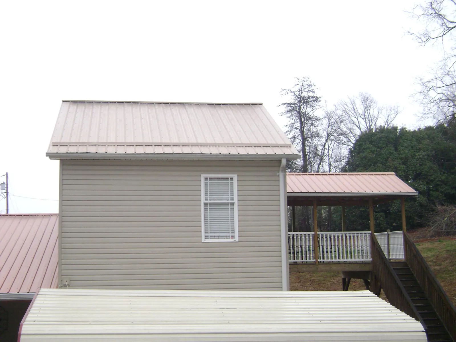 Tan metal roofs on a two story addition and attached porch, from a Roof Replacement job in Palisades Park