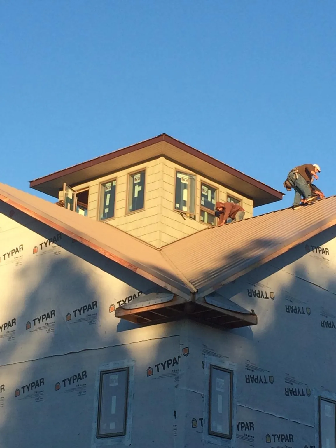 Roofers working around a rooftop cupola on a new metal roof at sunset — Roof Waterproofing in Palisades Park by Roofing Brothers